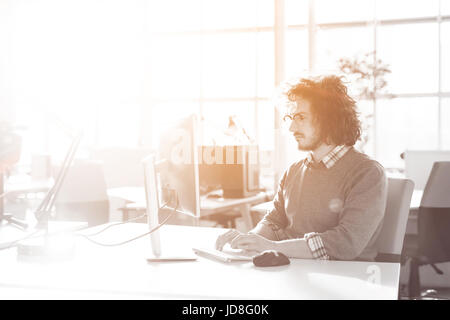Giovane imprenditore programer nella grande e luminosa office a lavorare utilizzando il computer Foto Stock