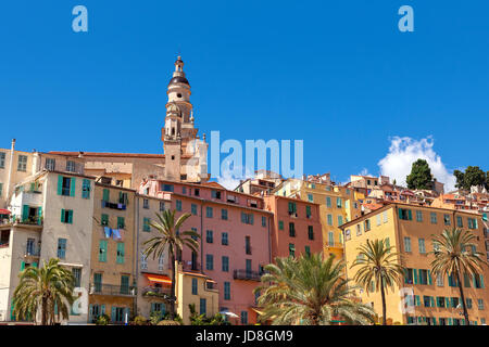 Torre campanaria tra le vecchie case colorate di Menton sotto il cielo blu sulla Riviera Francese. Foto Stock