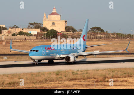 Viaggi aerei nell'Unione europea. Neos Boeing 737-800 volo all'atterraggio sulla pista di aeroporto di Malta, con Ta' Loretu Cappella, Gugja, in background Foto Stock