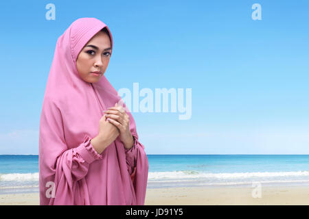 Ritratto di musulmani asiatici donna con hijab pregare Dio sulla spiaggia Foto Stock