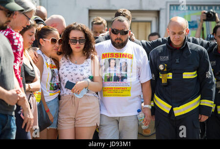 Fighfighters e membri del pubblico in Latymer Centro Comunitario di osservare un minuto di silenzio vicino alla Torre Grenfell nella zona ovest di Londra dopo un incendio si propagò edificio a 24 piani sulla mattina di mercoledì. Foto Stock