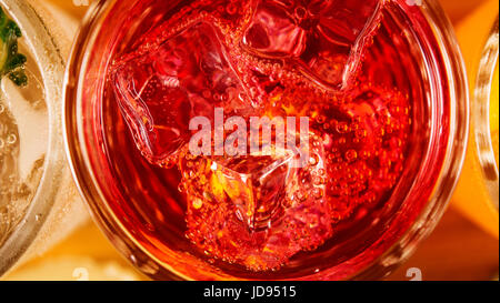 Bolle su cubetti di ghiaccio in un bicchiere con un cocktail rosso vista superiore Foto Stock