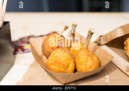 Fried le cosce di pollo in pastella su un pallet di cartone a food festival Foto Stock