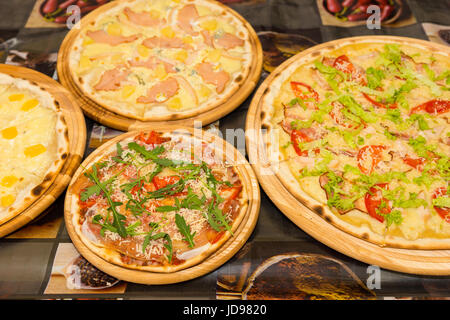 Una deliziosa pizza con varietà di condimenti e formaggio su vassoi di legno a outdoor food festival Foto Stock