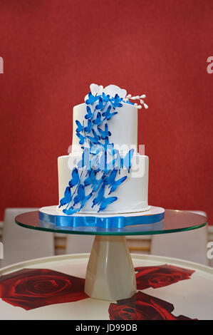 Torta di Nozze con farfalle blu sui bicchieri tavola. Foto Stock