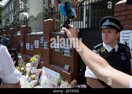 A seguito dell'attacco contro un gruppo di uomini musulmani al di fuori del parco di Finsbury moschea che ha ucciso una persona e gravemente ferito un altro dieci, hanno incontrato i funzionari di polizia a guardia della costruzione islamica dove i fiori sono stati lasciati, il 19 giugno 2017, nel quartiere di Islington, Londra del nord Inghilterra. Foto Stock