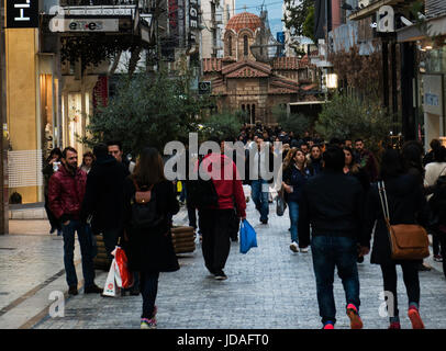 Gli acquirenti di occupato sul Ermou Street con thechurch di Panaghia Kapnikarea in background. Foto Stock