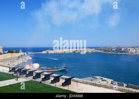 Il Cannone di mezzogiorno nella batteria a salve visto dall'Upper Barrakka Gardens con vedute sulla baia verso Fort Rikasoli, Valletta, Malta, l'Europa. Foto Stock