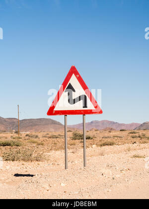 Segnale di avvertimento curve strette sulla strada di solitario sul deserto del Namib, Namibia, Africa. Foto Stock