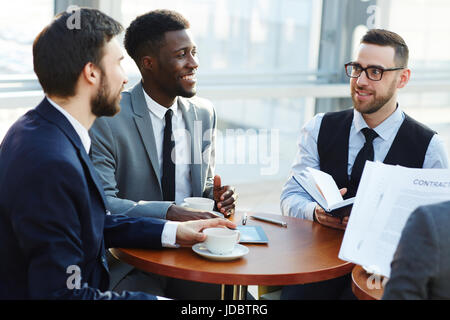 Gruppo di business sorridente persone per discutere i termini del contratto e la documentazione necessaria per rendere accordo di partenariato Foto Stock