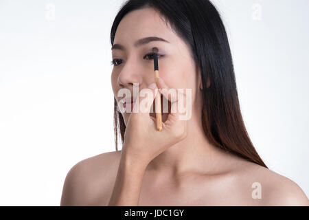 Make-up artist applicando il colore marrone ombretto compongono sulla bella asiatica del modello di occhio Foto Stock