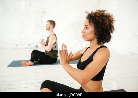 Vista laterale della giovane donna africana fare yoga in palestra Foto Stock