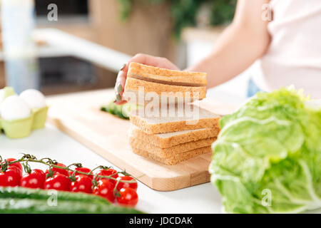 Close up ritratto di una donna che fa i panini con verdure su un tagliere Foto Stock