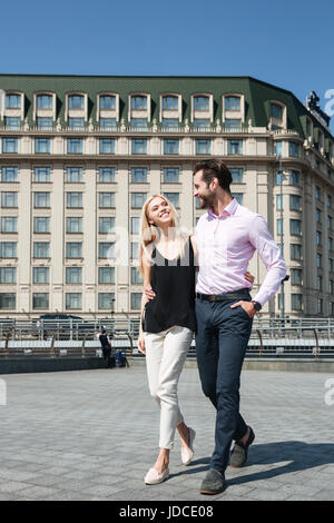 A tutta lunghezza shot di abbastanza giovane, allegro fiducioso uomo e bella donna bionda, passeggiate in strada Foto Stock