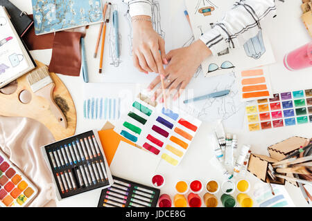 Vista dall'alto di una femmina di fashion designer che lavorano su disegni con della vernice sul suo posto di lavoro Foto Stock