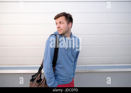 Bel giovane in un urban fashion lifestyle vestiti passeggiare e guardarsi indietro. Foto Stock
