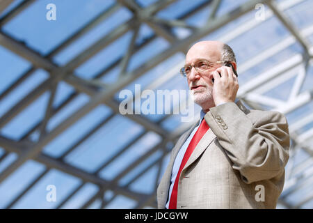 Imprenditore senior di camminare e di avere una conversazione al telefono Foto Stock