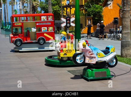 Una selezione di colorate giostre elettriche per bambini e bambini in un centro divertimenti in un centro commerciale locale a Playa Las Americasi Foto Stock