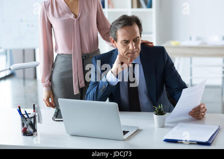 Imprenditore maturo e imprenditrice con il computer portatile e i documenti di lavoro in ufficio Foto Stock