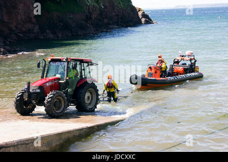 Scialuppa di salvataggio e dei battelli di salvataggio equipaggio a Hope Cove, Devon England. La scialuppa di salvataggio viene recuperato sul suo trattore e rimorchio dopo un viaggio per mare. Foto Stock