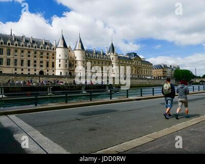 Due uomini a piedi lungo Parc Rives de Seine, guardando al passaggio di un imbarcazione turistica. Parigi, Francia Foto Stock