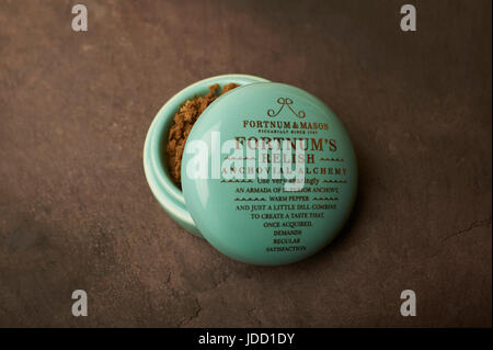Fortnum e Mason, Fortnum's Relish Anchovial alchimia in un piccolo vaso di porcellana con scritte in oro su un sfondo di ardesia Foto Stock
