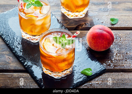 Peach tè freddo. Tè freddo con fette di pesche, menta e cubetti di ghiaccio da vicino. In casa dissetante bevanda estiva. Foto Stock
