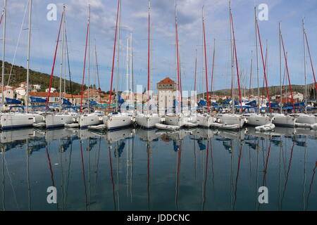 La mattina presto immagine di dodici Sunsail yachts riflettente nel porto di Marina, Croazia con torre in middke Foto Stock