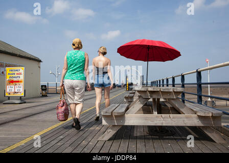 Legno tavoli da picnic & e sedie con ombrelloni rosso a Southport, Merseyside, Regno Unito. Regno Unito Meteo. Xx Giugno, 2017. Venti leggeri e lacunose nuvole sul lungomare di Southport Pier come passeggini godere la brezza del mare off sul mare irlandese. Patchy nuvole stanno dando un po' di sollievo dalle alte temperature, come villeggianti e turisti promenade giù il più lungo il molo di ferro nel Regno Unito. Foto Stock