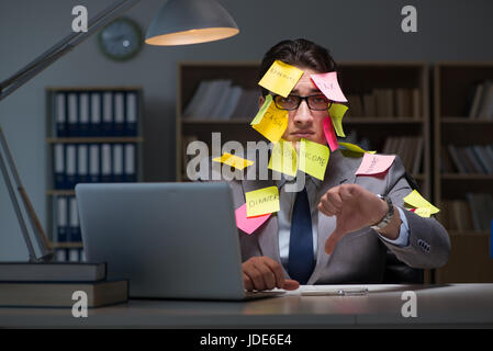 Uomo d'affari che soggiornano in ritardo per ordinare le priorità Foto Stock