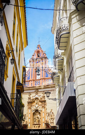 Strada stretta a Siviglia con una bella chiesa Foto Stock