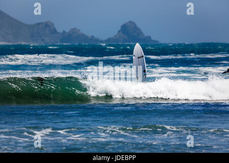 Surfer salviette in onda alla costa rocciosa Foto Stock