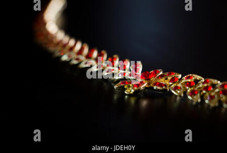 Collana in oro con pietre rosse di close-up su sfondo nero Foto Stock