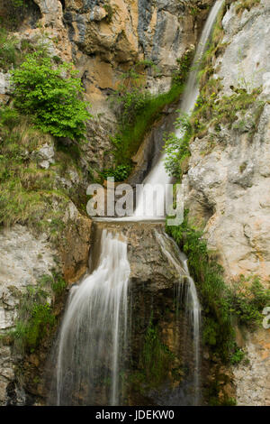 Cascata in un luogo nascosto sulle montagne. Cascata di oltre una parete di arrampicata Foto Stock