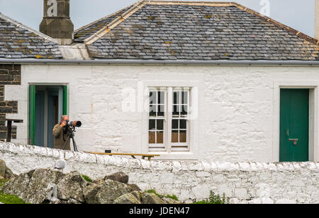 Wildlife Photographer con la fotocamera sul cavalletto e lungo la lente, la luce bassa osservatorio ornitologico, Isola di maggio, Firth of Forth, Scotland, Regno Unito Foto Stock