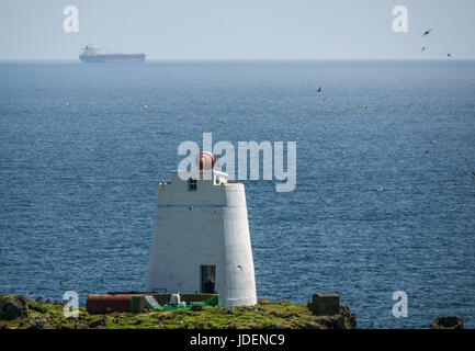 Bianco edificio rotondo struttura con grande sirena antinebbia, Isola di maggio, Firth of Forth, Scozia, con contenitore grande nave sull orizzonte Foto Stock