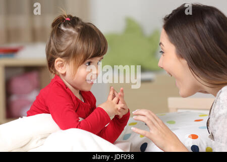 La madre e il bambino che indossa camicia rossa insieme giocando su un letto in camera da letto a casa Foto Stock
