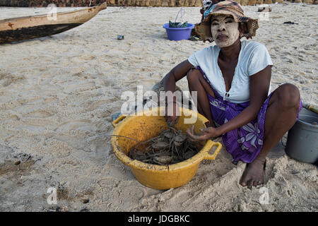 Sakalava donna con faccia Tabaky paint vendendo granchi, Morondava, Madagascar Foto Stock