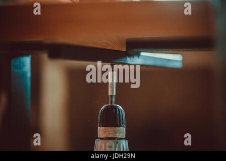 Uomo che utilizza un acciaio trapano e cacciavite usuale serrando la vite in un asse di legno. Il processo per la fabbricazione di mobili. soft focus. shallow dof. Foto Stock