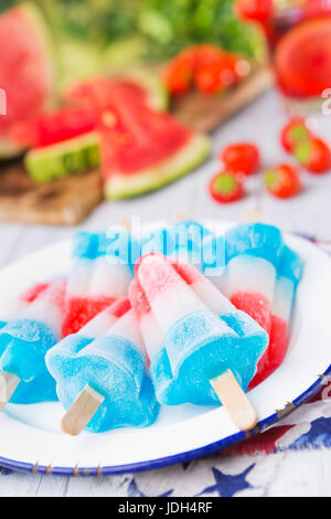 In casa bianco-rosso-e-blu popsicles su un tavolo esterno con limonata fresca in background. Foto Stock