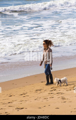Donna cane a camminare lungo la riva del mare a Bournemouth Beach mare a Bournemouth Dorset in aprile Foto Stock