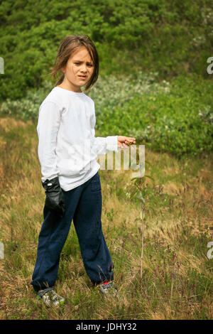 Ragazzo con i capelli lunghi e un guanto nero in posa con tree alberello Foto Stock