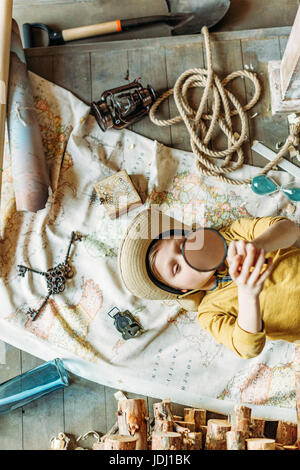 Vista superiore del ragazzino hat giacente sulla mappa con lente di ingrandimento Foto Stock