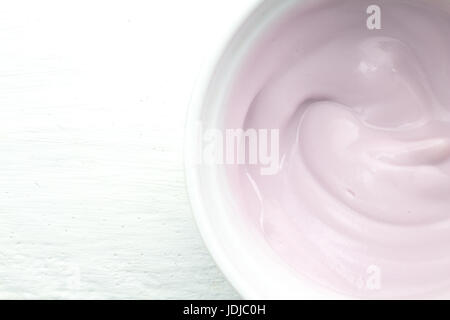 Cremosa di colore naturalmente rasberry yogurt alla frutta in bianco ciotola di vetro bianco sul tavolo di legno vicino la vista superiore fotografia Foto Stock