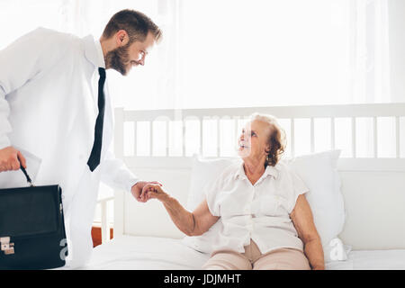 Fornire assistenza e supporto per anziani. Visita medico paziente anziano a casa. Foto Stock