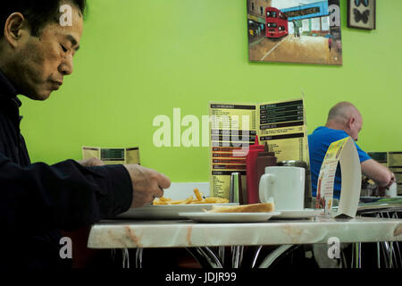 Maschio di mangiare in un "grassa" Spoon Cafe fry-colazione London REGNO UNITO Foto Stock