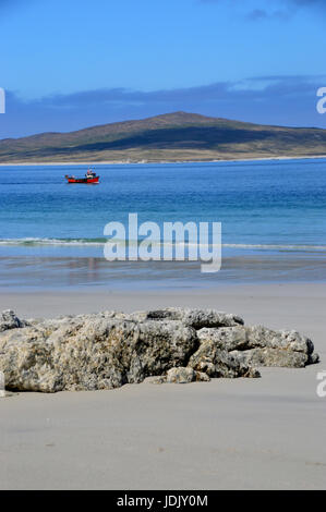 Un piccolo rosso barca da pesca passando West Beach sull'Isola di Berneray su North Uist con l'isola di Pabbay in background, Ebridi Esterne, Foto Stock