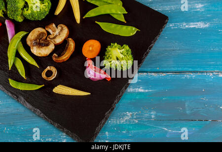 Raccolta di verdure fresche a foglia verde posto sulla pietra nera Foto Stock