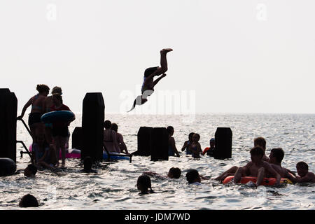 Aberystwyth Wales UK, mercoledì 21 giugno 2017 UK Meteo: gruppi di ragazzi adolescenti e ragazze il raffreddamento mediante il salto in mare al largo del molo a Aberystwyth alla fine Solstice giorno e ciò che ci si aspetta di essere l'ultimo giorno del corrente periodo di caldo e afoso meteo come il calore di mini-onda continua oggi oltre le isole britanniche. Il Met Office ha avvertito di heavy rain e temporali con la possibilità di localizzare le inondazioni che hanno colpito gran parte del Regno Unito nella prossima 24 Ore come il sistema meteo inizia a rompersi dopo molti giorni di registrare hight temperature Credito: keith morris/Alamy Live News Foto Stock