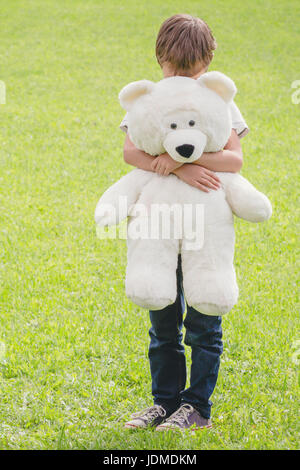 Triste ragazzo abbracciando hid Teddy bear. Per Esterno, giorno d'estate. Foto Stock